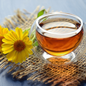 Glass of chamomile tea with fresh chamomile flower next to it. Foods that help you sleep and relax.
